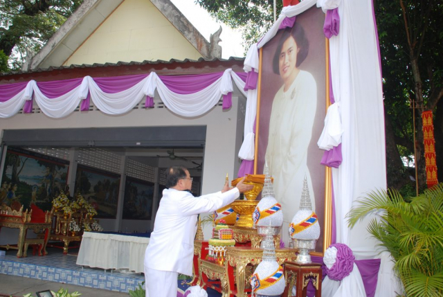 ประธานในพิธี ถวายความเคารพพระฉายาลักษณ์หน้าอุโบสถ แล้วถือผ้าไตรพระราชทาน และถวายความเคารพ