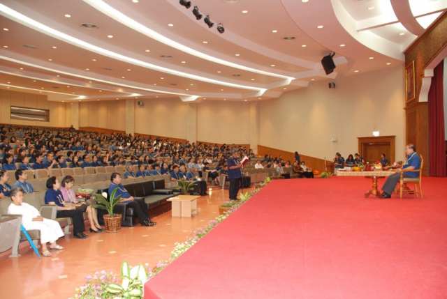 รศ.ดร.วันชัย ศิริชนะ อธิการบดี เดินขึ้นเวที และนั่งเก้าอี้ที่จัดไว้