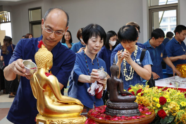 ผู้เข้าร่วมพิธี สรงน้ำพระพุทธรูปพระเจ้าล้านทองเฉลิมพระเกียรติฯ และพระรูปสมเด็จพระศรีนครินทราบรมราชชนนี (จำลอง) บริเวณโถงทางเข้าหอประชุมสมเด็จย่า